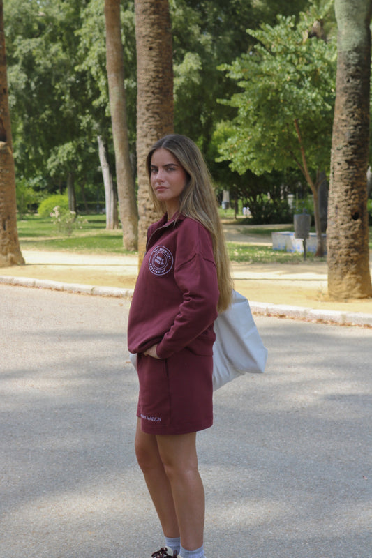 Sudadera burdeos con cremallera abierta, cuello alto y silueta oversized, vista lateral.